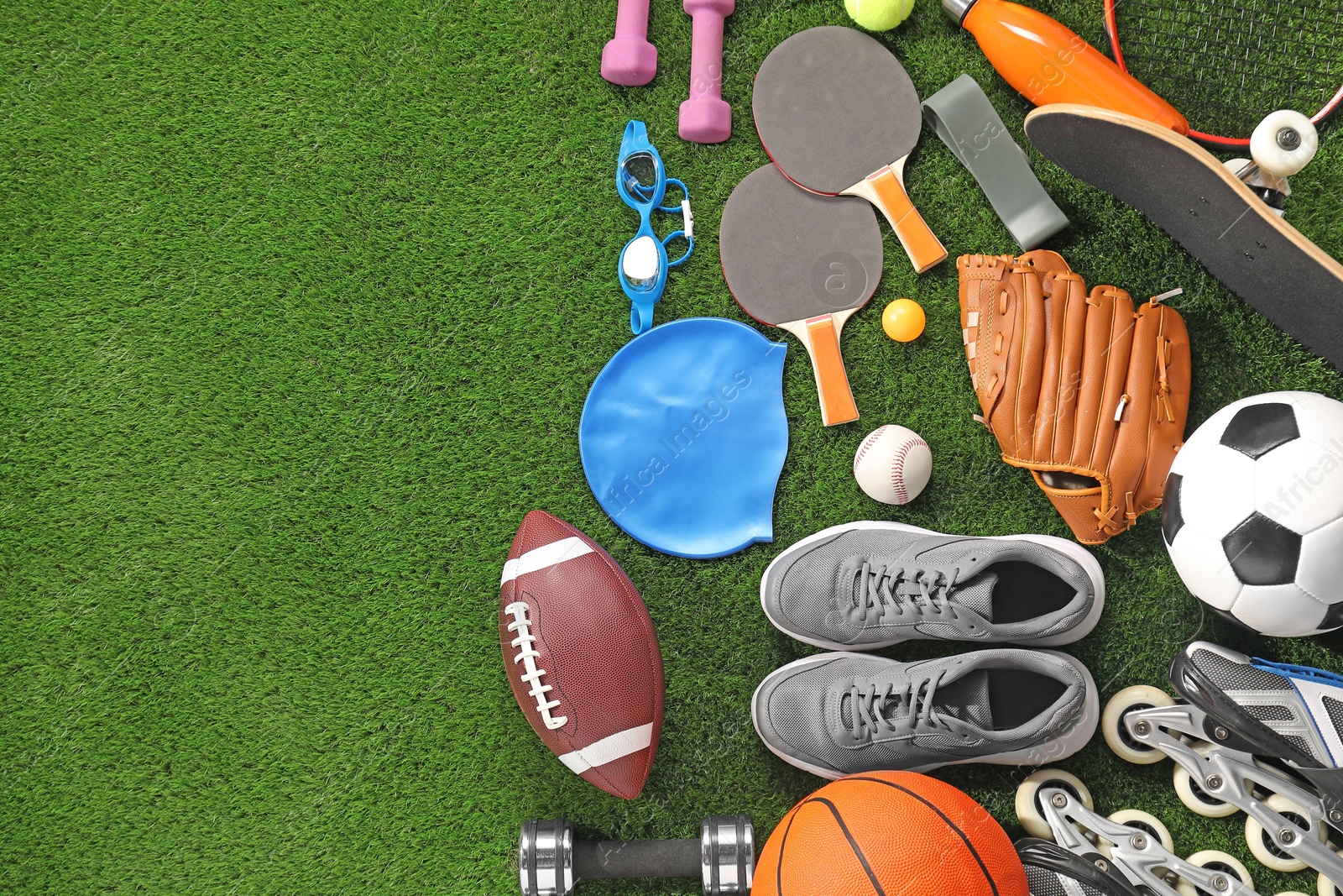 Photo of Different sport equipment on artificial grass, flat lay. Space for text