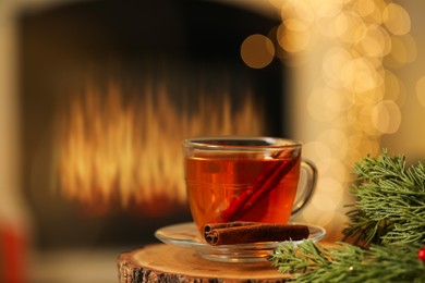 Photo of Cup of tea with cinnamon on table against blurred Christmas lights, bokeh effect. Space for text