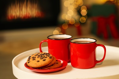 Photo of Tasty cocoa in cups and chocolate chip cookies on table against blurred Christmas lights. Bokeh effect