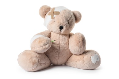 Photo of Teddy bear with bandages, adhesive medical plasters and thermometer isolated on white