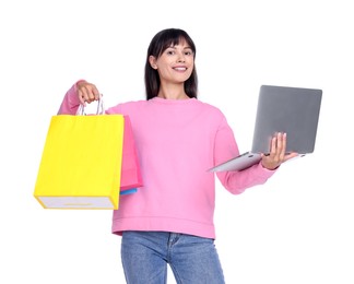 Photo of Internet shopping. Smiling woman with laptop and colorful bags on white background