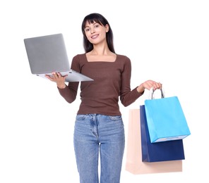 Photo of Internet shopping. Happy woman with laptop and colorful bags on white background