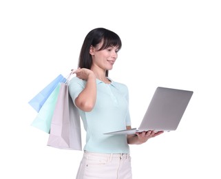 Photo of Internet shopping. Happy woman with laptop and colorful bags on white background