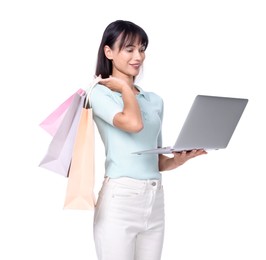 Photo of Internet shopping. Happy woman with laptop and colorful bags on white background