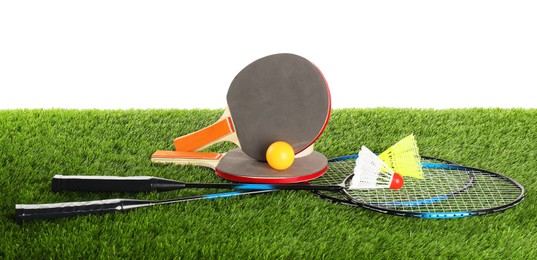 Photo of Different sport equipment on artificial grass isolated on white