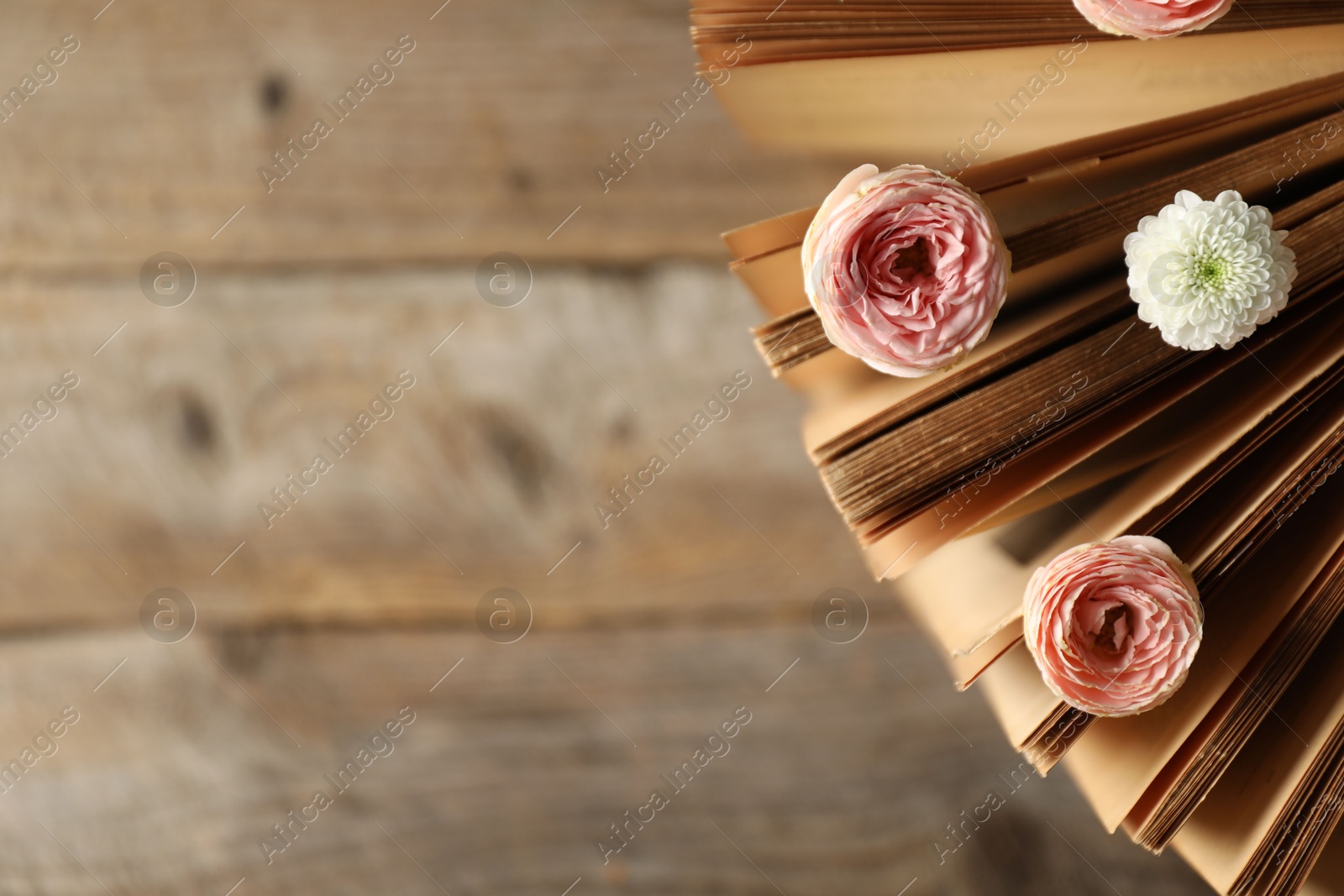 Photo of Book with beautiful flowers on wooden table, top view. Space for text