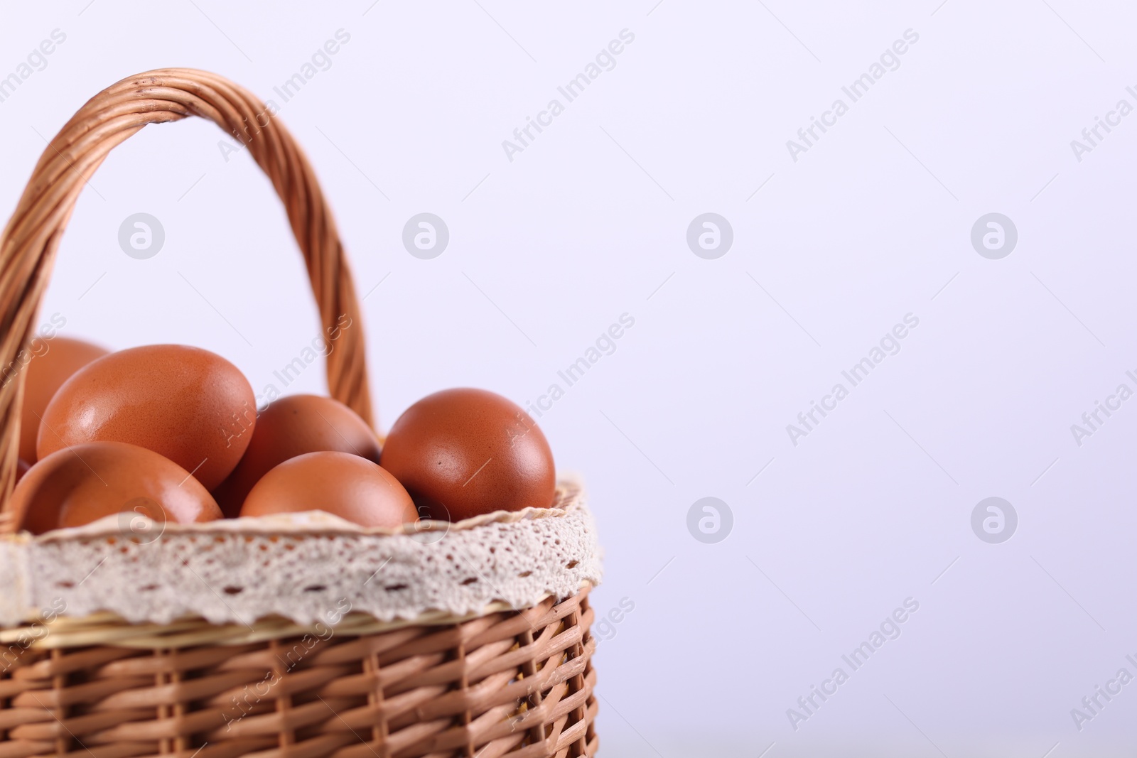 Photo of Wicker basket with fresh eggs on white background, closeup. Space for text