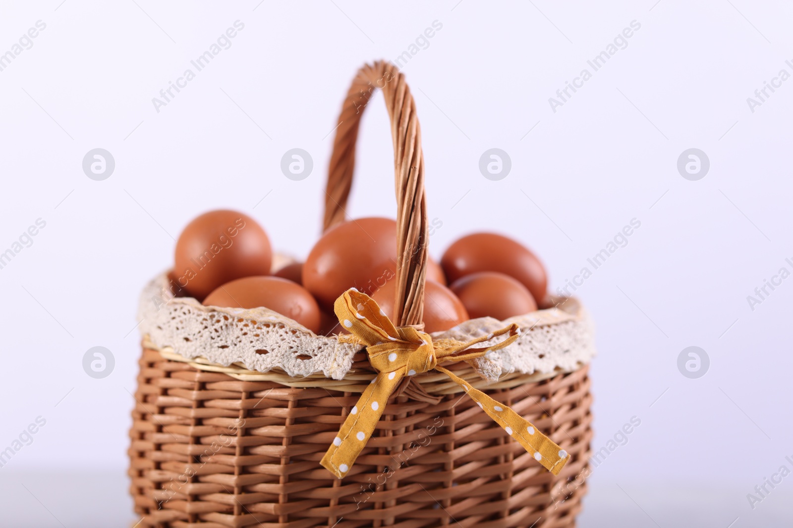 Photo of Wicker basket with fresh eggs on white background, closeup