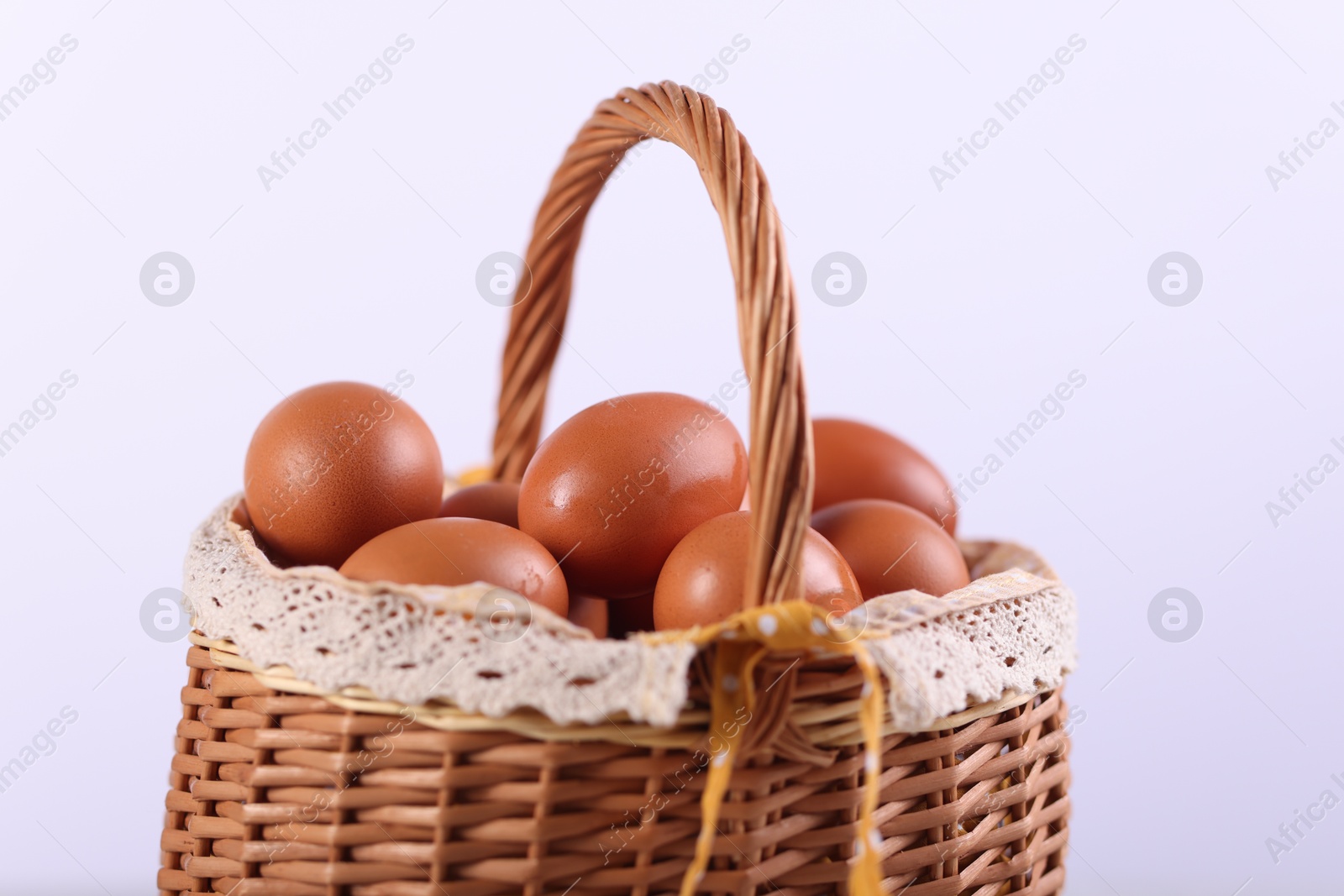 Photo of Wicker basket with fresh eggs on white background, closeup