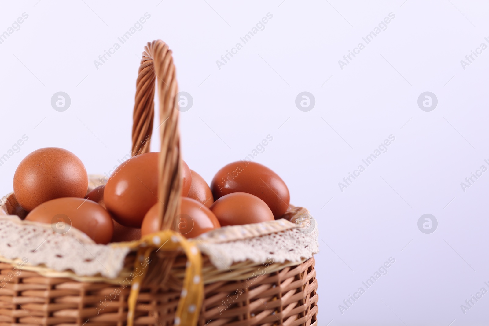 Photo of Wicker basket with fresh eggs on white background, closeup. Space for text