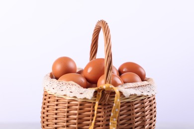 Photo of Wicker basket with fresh eggs on white background, closeup