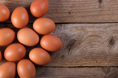 Photo of Many fresh eggs on wooden table, flat lay. Space for text