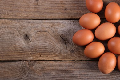 Photo of Many fresh eggs on wooden table, flat lay. Space for text