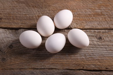 Photo of Many fresh eggs on wooden table, flat lay