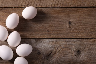 Photo of Many fresh eggs on wooden table, flat lay. Space for text