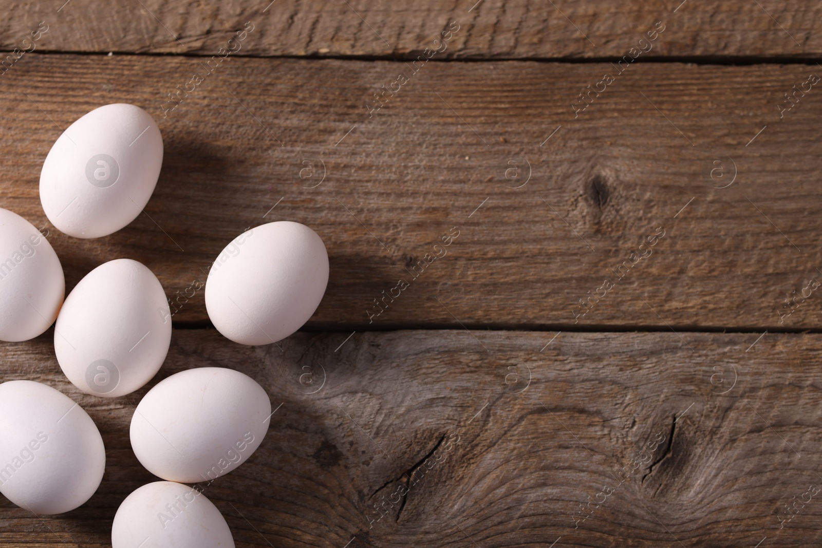 Photo of Many fresh eggs on wooden table, flat lay. Space for text