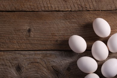 Photo of Many fresh eggs on wooden table, flat lay. Space for text