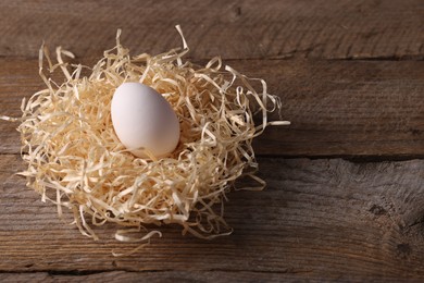 Photo of One fresh egg on wooden table, closeup. Space for text