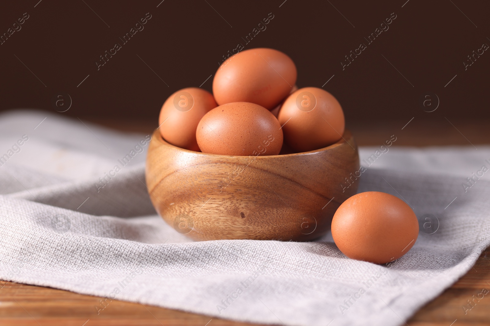 Photo of Fresh eggs in bowl on wooden table, closeup