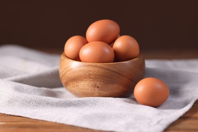 Photo of Fresh eggs in bowl on wooden table, closeup