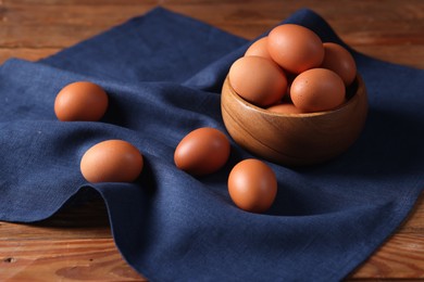 Photo of Fresh eggs and bowl on wooden table, closeup