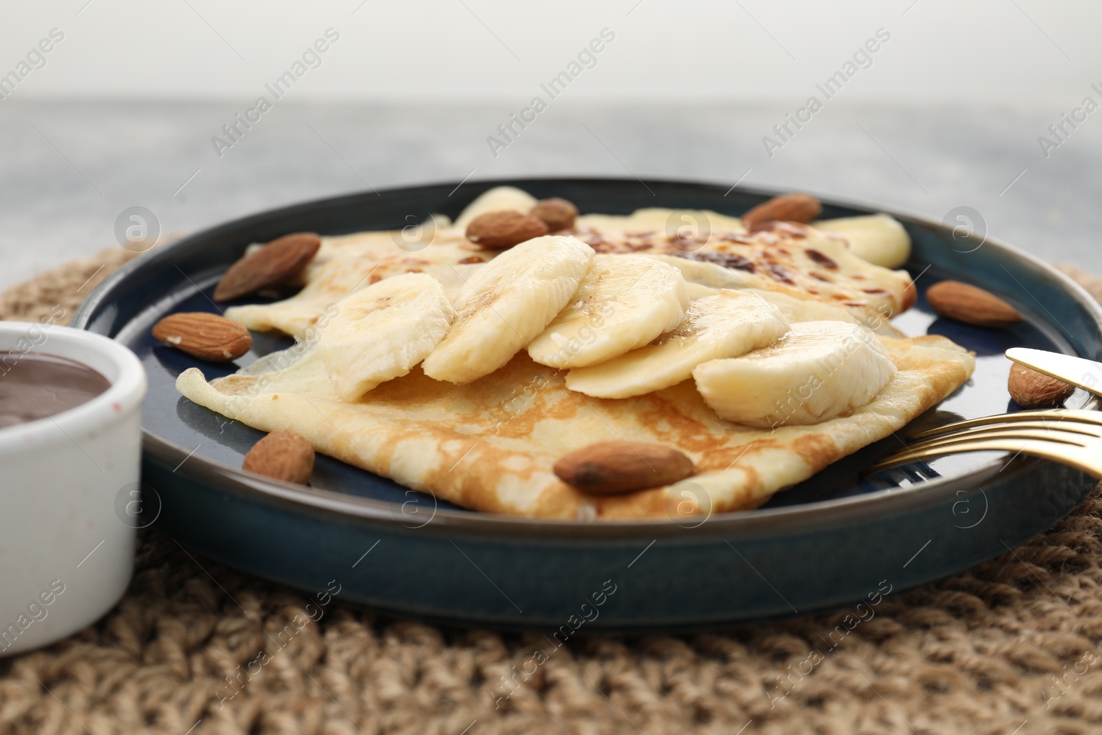 Photo of Delicious crepes with banana and almonds served on table, closeup