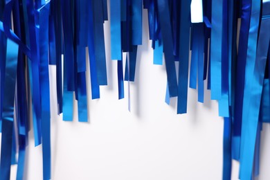 Photo of Shiny blue foil curtain on white background, closeup