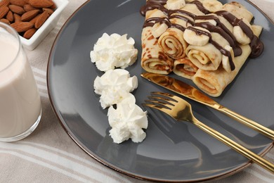 Delicious crepes with banana, chocolate sauce and whipped cream served on table, closeup