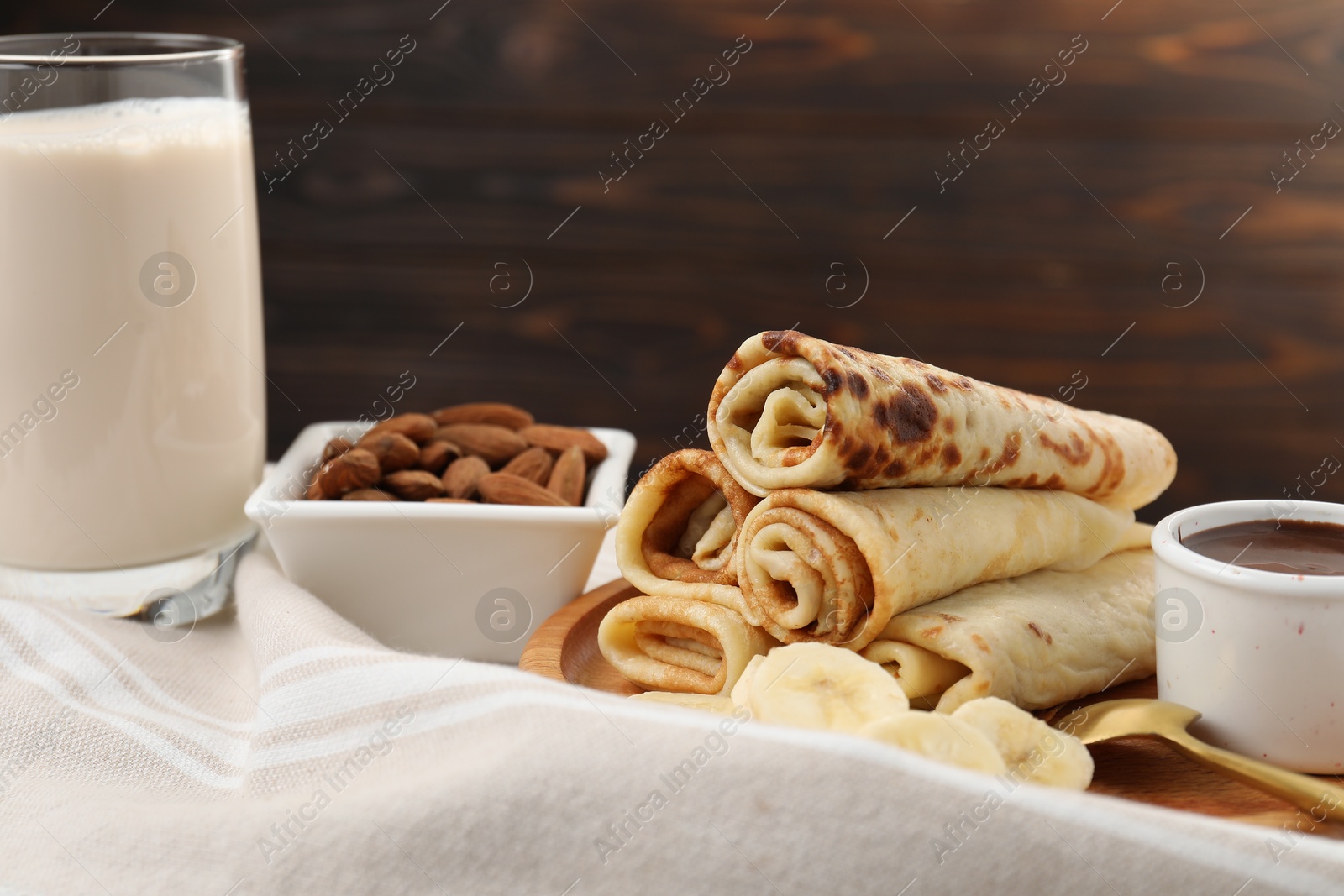 Photo of Delicious crepes served with chocolate sauce and banana on table, closeup