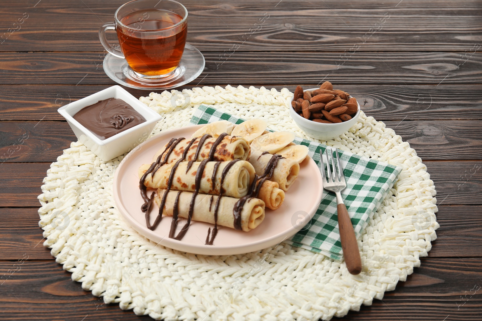 Photo of Delicious crepes with chocolate sauce and banana served on wooden table