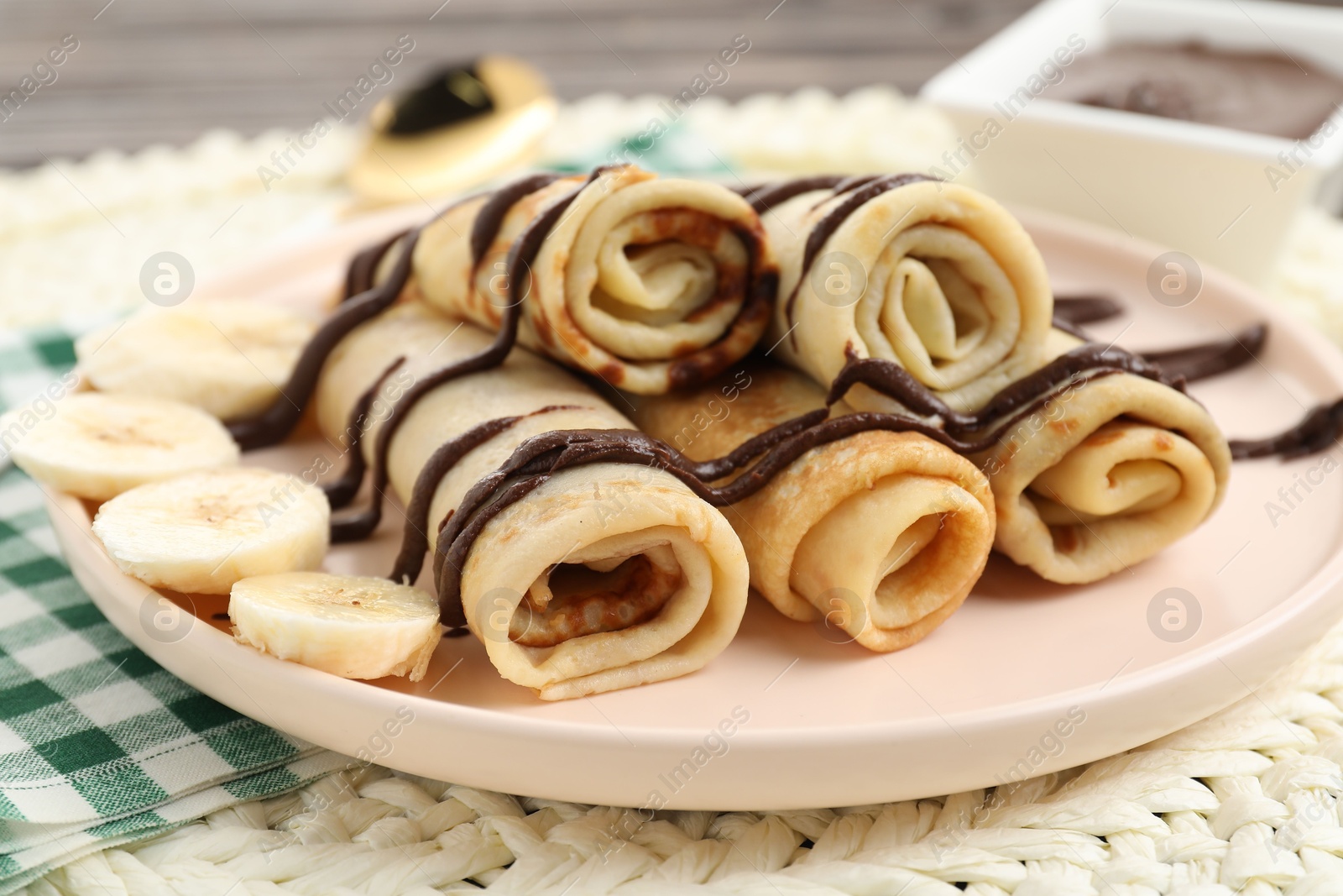 Photo of Delicious crepes with chocolate sauce and banana on table, closeup