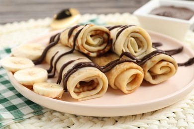 Photo of Delicious crepes with chocolate sauce and banana on table, closeup