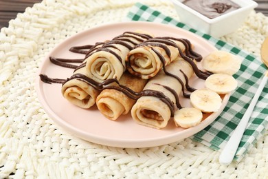 Delicious crepes with chocolate sauce and banana on table, closeup