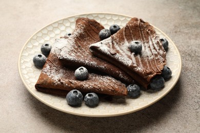 Photo of Delicious chocolate crepes with blueberries on grey table, closeup