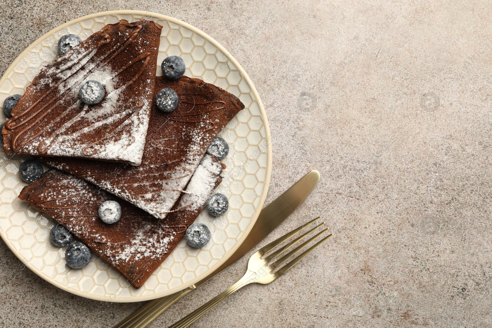 Photo of Delicious chocolate crepes with blueberries served on grey table, top view. Space for text