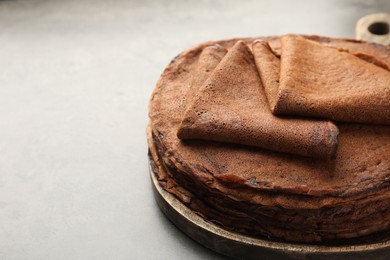 Photo of Stack of delicious chocolate crepes on grey table, closeup. Space for text