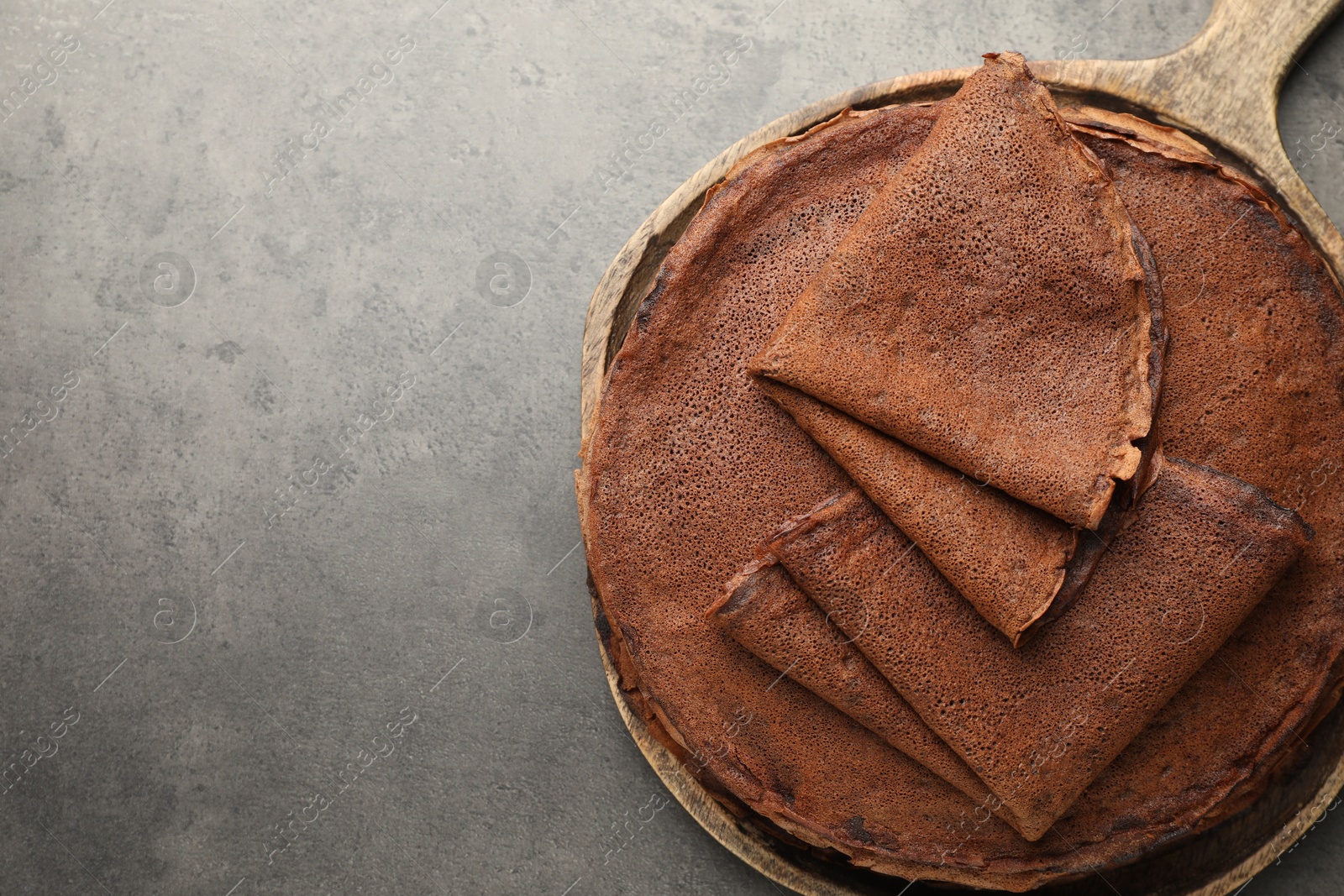 Photo of Delicious chocolate crepes on grey table, top view. Space for text