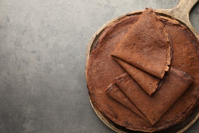 Photo of Delicious chocolate crepes on grey table, top view. Space for text