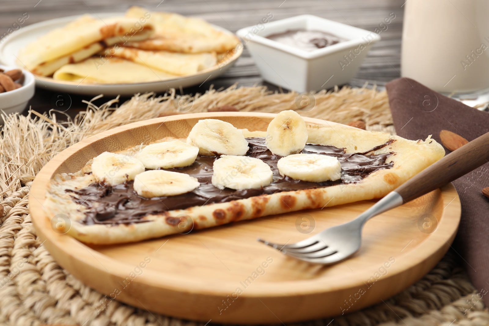 Photo of Delicious crepe with chocolate paste and banana served on table, closeup