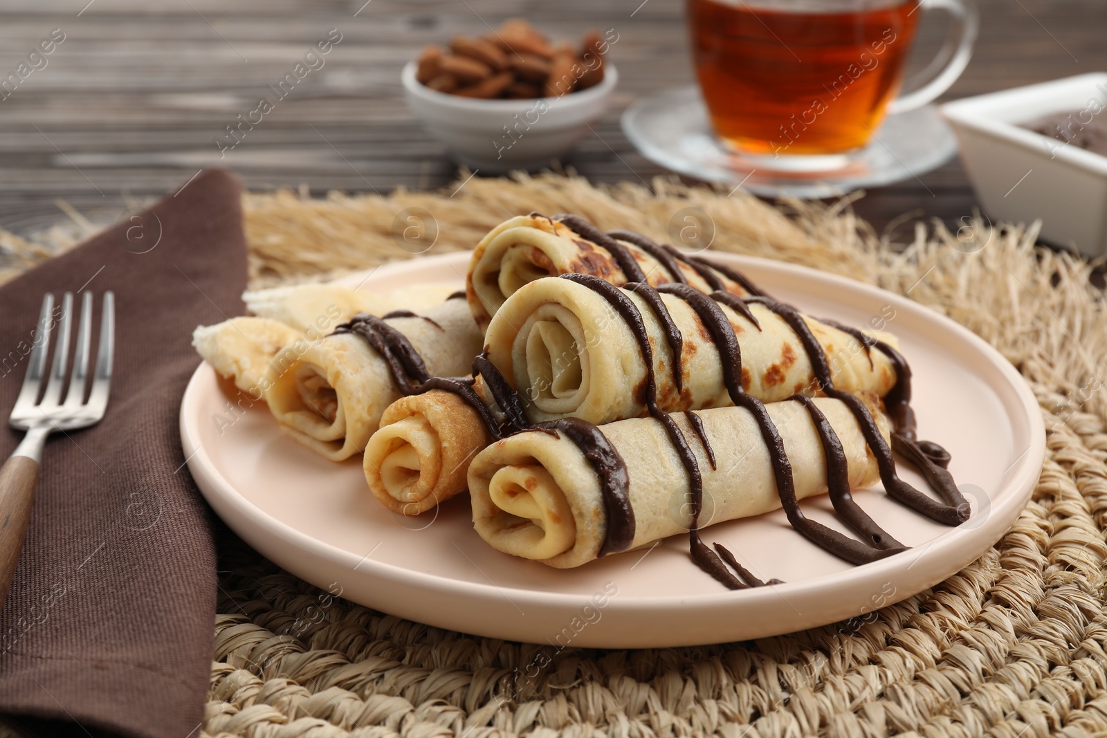 Photo of Delicious crepes with chocolate sauce served on wooden table