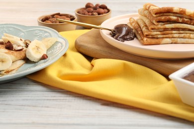 Delicious crepes served with chocolate paste and nuts on wooden table, closeup