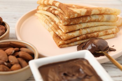 Photo of Delicious crepes with chocolate paste and nuts on table, closeup