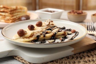 Delicious crepe with banana, nuts and chocolate sauce on table, closeup