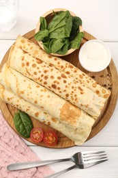 Photo of Tasty rolled crepes with cottage cheese and spinach served on white wooden table, flat lay