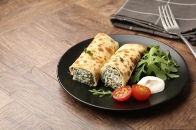 Photo of Tasty rolled crepes with cottage cheese and spinach served on wooden table, closeup. Space for text