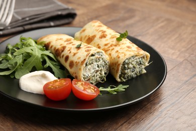 Photo of Tasty rolled crepes with cottage cheese and spinach served on wooden table, closeup