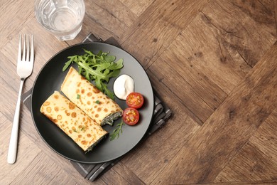 Photo of Tasty rolled crepes with cottage cheese and spinach served on wooden table, flat lay. Space for text