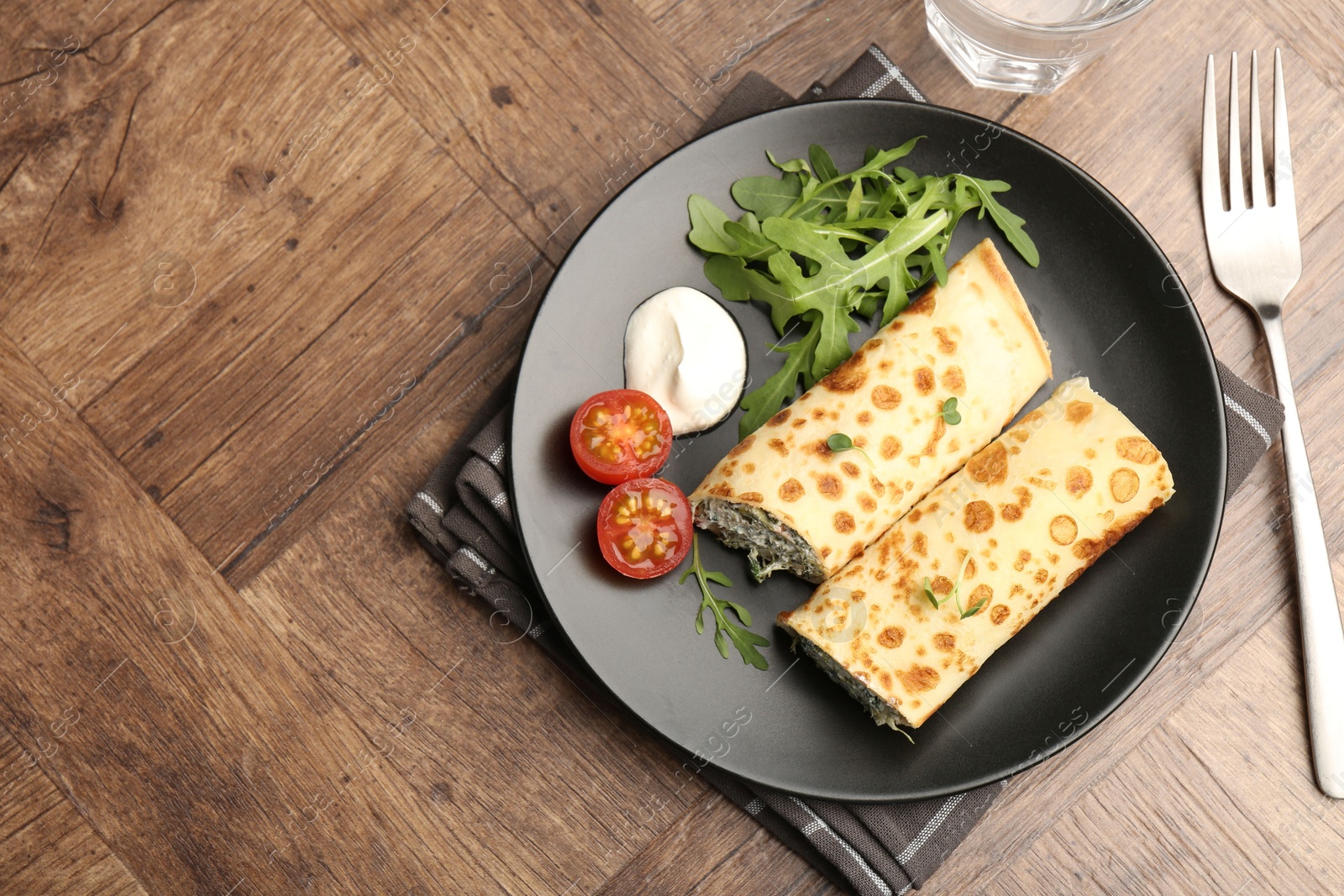 Photo of Tasty rolled crepes with cottage cheese and spinach served on wooden table, flat lay. Space for text