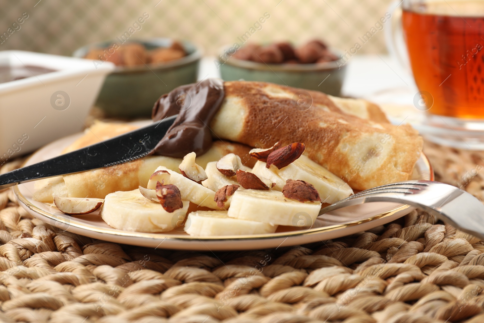 Photo of Delicious crepes with banana, nuts and chocolate paste on table, closeup