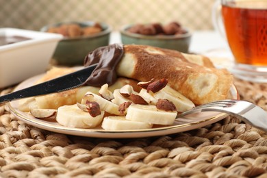 Photo of Delicious crepes with banana, nuts and chocolate paste on table, closeup